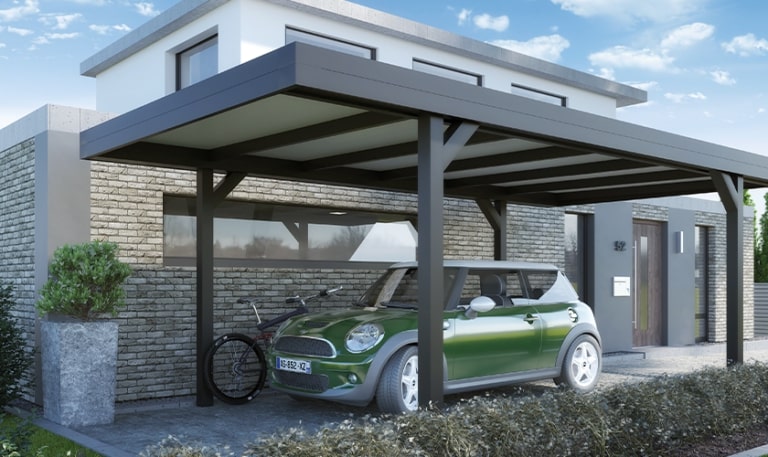 Ein grünes Auto unter einem modernen Carport neben einem Fahrrad. Haus mit Steinmauer im Hintergrund.