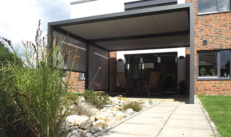 Moderne Terrasse mit Überdachung und Gartenblick, Ziegelwände, Holzmöbel, Kieselsteine.