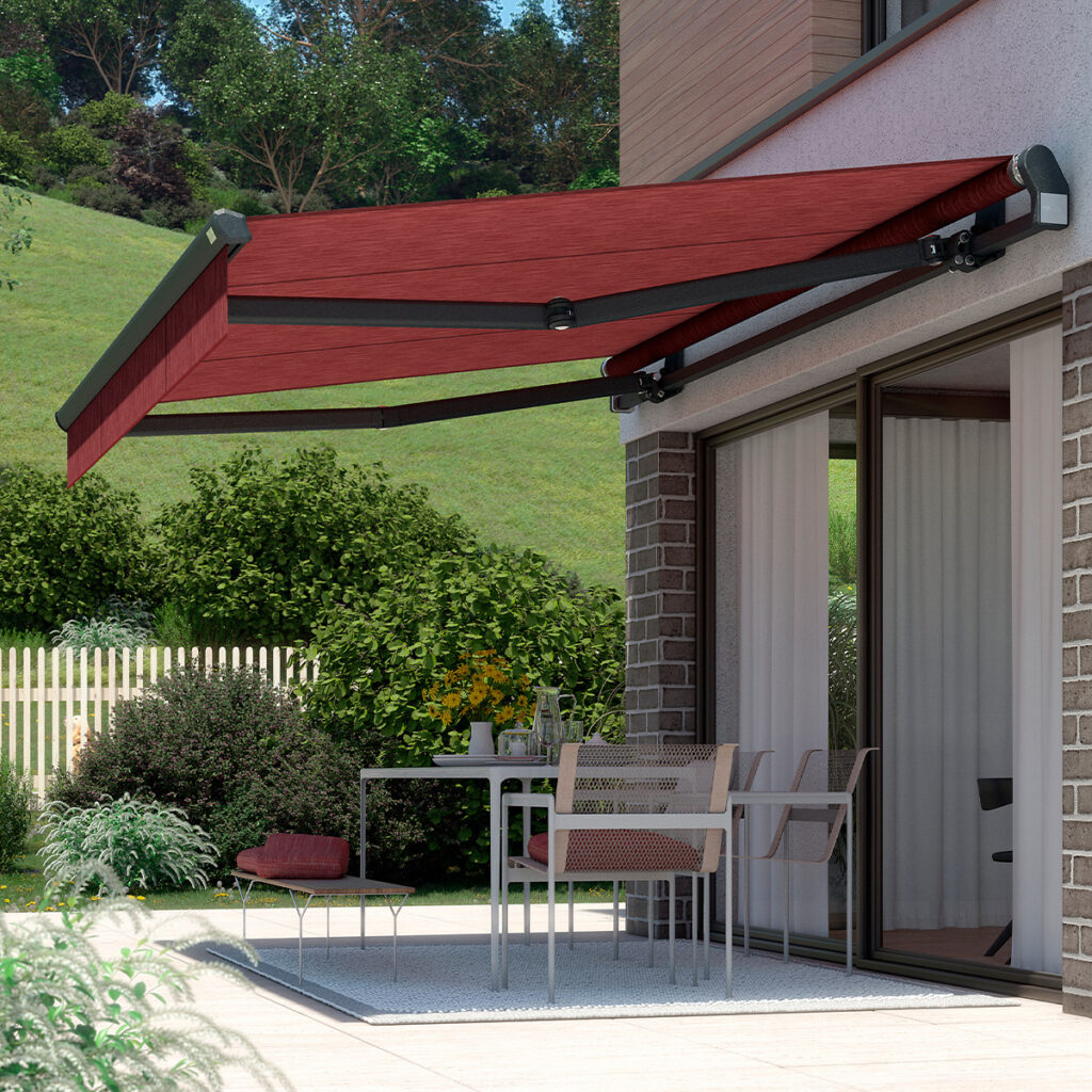 Eine rote Markise über einer Terrasse mit Tisch und Stühlen vor einem modernen Haus.